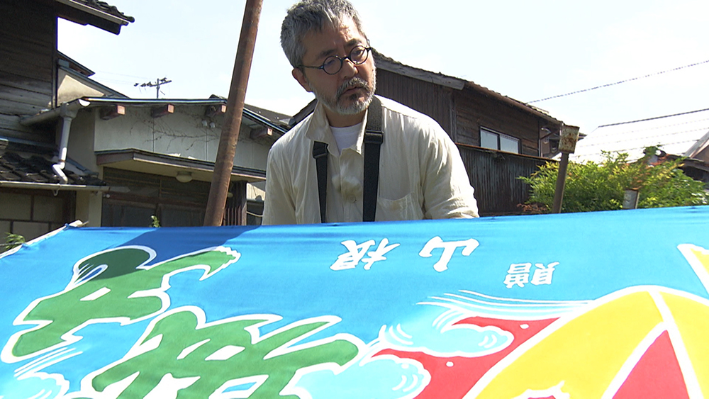 Hishikawa admires the finished banner.
