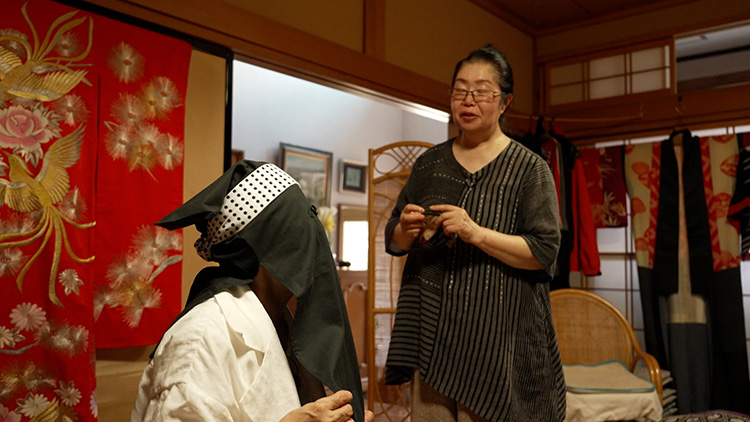 Koike wearing Hikosazukin hood and low-brimmed straw hats