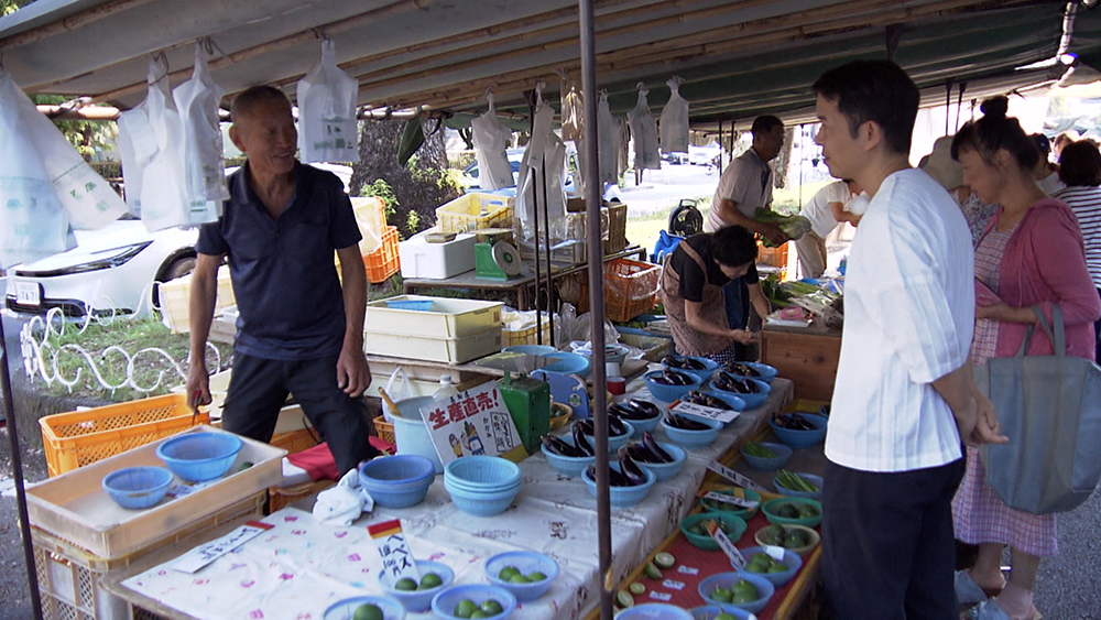 Miyamae interviews a man selling citrus fruits